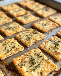 crackers with cheese and herbs are on a baking sheet