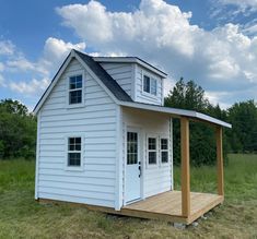 a small white house sitting on top of a wooden platform in the middle of a field