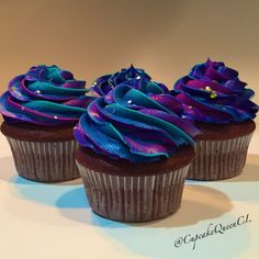 three chocolate cupcakes with purple and blue frosting