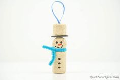 a cork snowman ornament with a blue scarf around it's neck