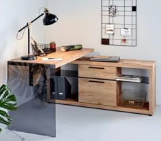 a desk with drawers and a lamp on it in a white room next to a plant