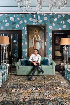 a man sitting on top of a couch in a living room next to two lamps