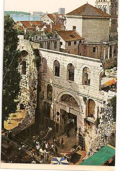 an old postcard shows the entrance to a building with people walking around it and some buildings in the background