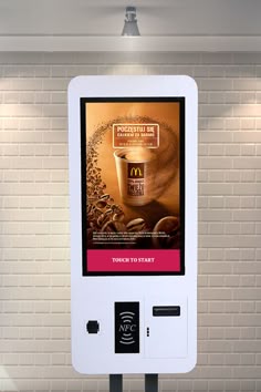 an advertisement for mcdonald's coffee is displayed on a kiosk in front of a brick wall