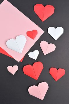 folded paper hearts on top of a pink and white card with one red heart in the middle