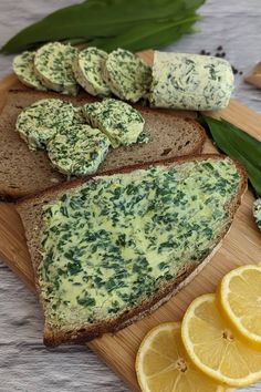 slices of bread topped with spinach and cheese on a cutting board next to sliced lemons