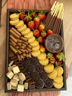 a tray filled with cookies, strawberries and other desserts on top of a wooden table