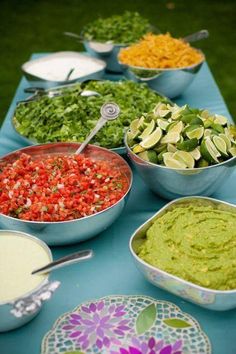 a table topped with bowls filled with different types of food next to salads and dips