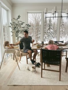 a man sitting at a table with two children and a dog in front of him