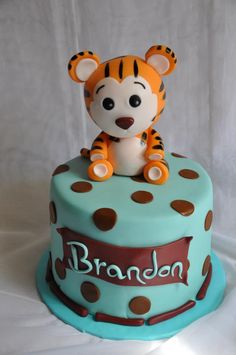 a blue cake with a tiger on top and brown polka dots around the edges that says brandon