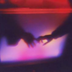 two hands touching each other in front of a television screen with red and blue lights