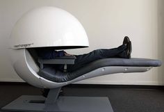 a man laying on top of a chair with a large white object in the middle