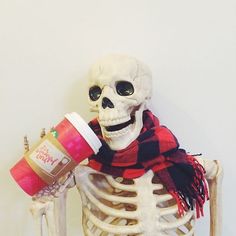 a skeleton holding a coffee cup in it's right hand and wearing a scarf
