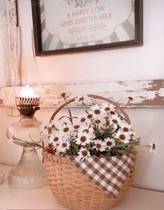 a basket filled with daisies sitting on top of a table next to a candle
