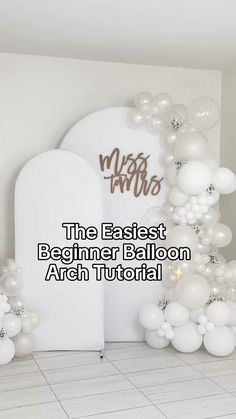 balloon arch in the middle of a room with white balloons on it and words that read,