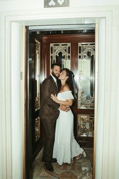 a man and woman standing in front of a door with their arms around each other