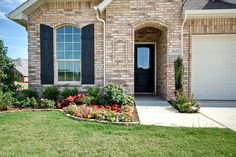 a brick house with flowers in the front yard