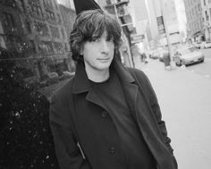 a man standing on the side of a street next to tall buildings