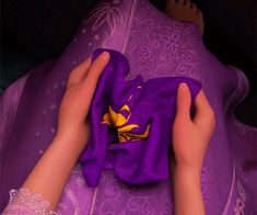 a person laying on top of a purple bed covered in a purple blanket with a yellow flower