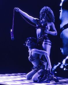 two women in costumes performing on stage with one holding the other's leg up