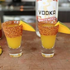 three shot glasses filled with orange juice and garnished with gold flecks