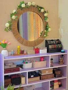 a purple bookcase with flowers on it and a round mirror above the bookshelf