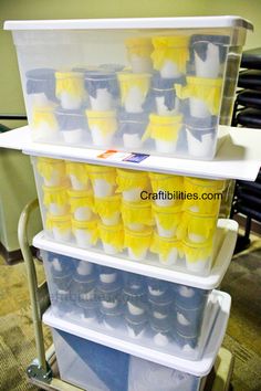 three plastic containers stacked on top of each other with yellow and white cups in them