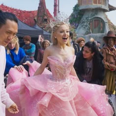 a woman in a pink dress is surrounded by people