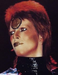 a close up of a person with red hair and eyeliners on their face