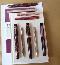 five different types of fountain pens on top of a white paper with gold trimmings
