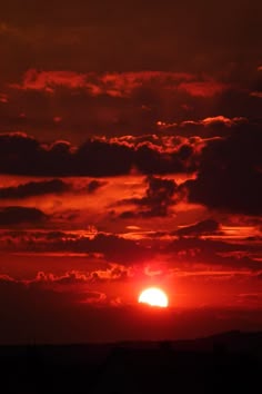 the sun is setting behind some clouds in the sky with red and orange colors on it