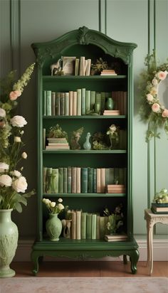 a green bookcase with many books on top of it next to a vase filled with flowers