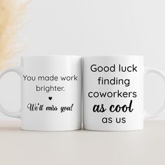 two white coffee mugs sitting on top of a table