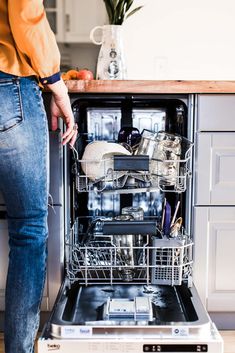 a person standing in front of an open dishwasher