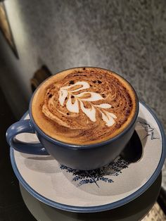 a cappuccino is sitting on top of a saucer with blue trim
