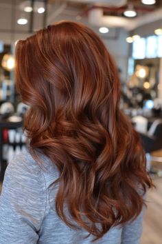 Person with long, wavy auburn hair in a salon setting.