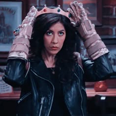 a woman in a leather jacket holds her hands up to her head