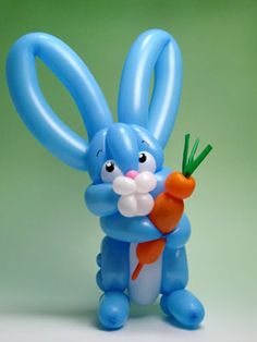 a blue balloon rabbit holding a carrot in its hand and looking at the camera, on a green background