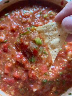 a tortilla chip being dipped with salsa