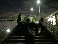 several people are walking up some stairs at night time, with one person on the other side