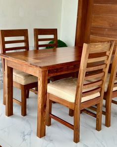 a wooden table and chairs sitting next to each other on a white tile floor in front of a wood paneled wall