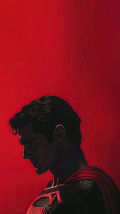 a man in a superman suit standing against a red background