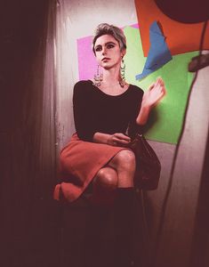 a woman is sitting on the wall with her hand in her pocket