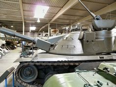 an old tank is on display in a building with other tanks and equipment around it