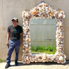 a man standing in front of a mirror made out of seashells