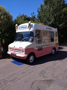 an ice cream truck is parked on the side of the road with trees in the background