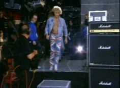 a man is walking down the runway in front of other men wearing blue and white outfits