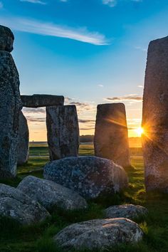 the sun is setting at stonehenge monument in england, with grass and rocks surrounding it