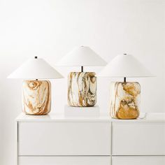 three marble lamps sitting on top of a white dresser next to each other in a room