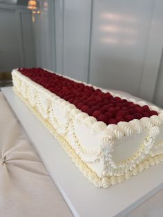 a large white cake with red and white frosting on it's side sitting on a table